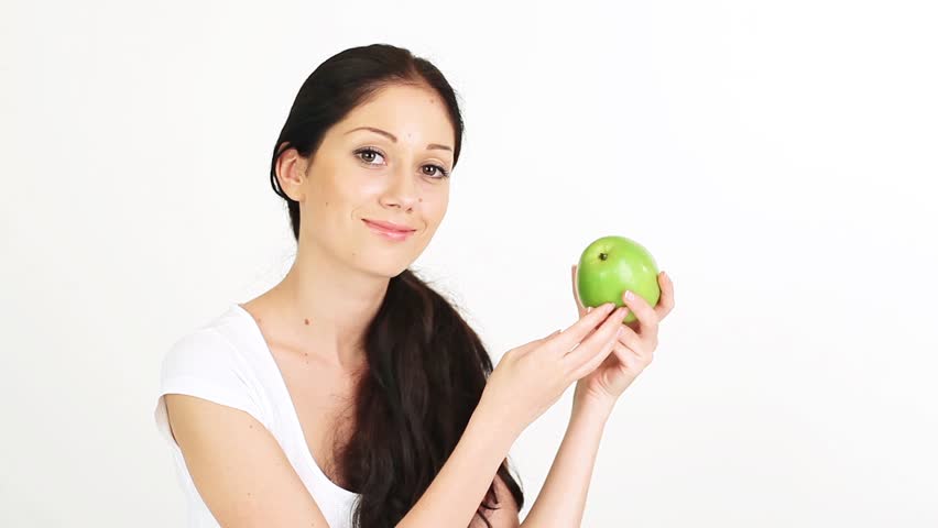 Young attractive woman playing with and offering green apple on white