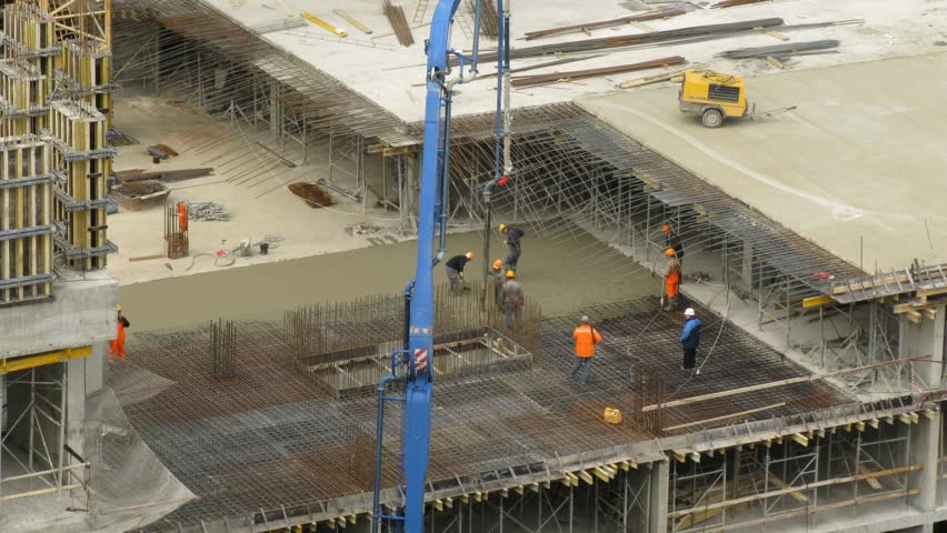 construction workers pour concrete using concrete pump 