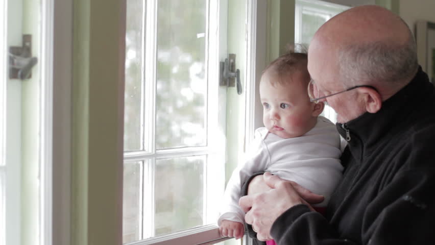 Grandfather holding his granddaughter near window
