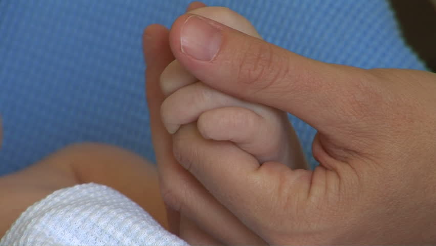 Mother holding newborn baby hand