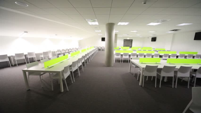  Light room without windows, white elongated tables and chairs.