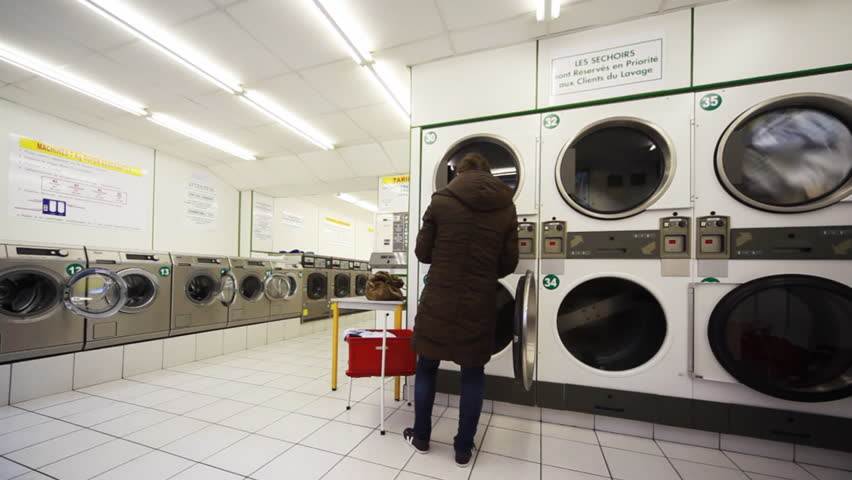 public laundry with large washing machines, woman puts in one drum clothes