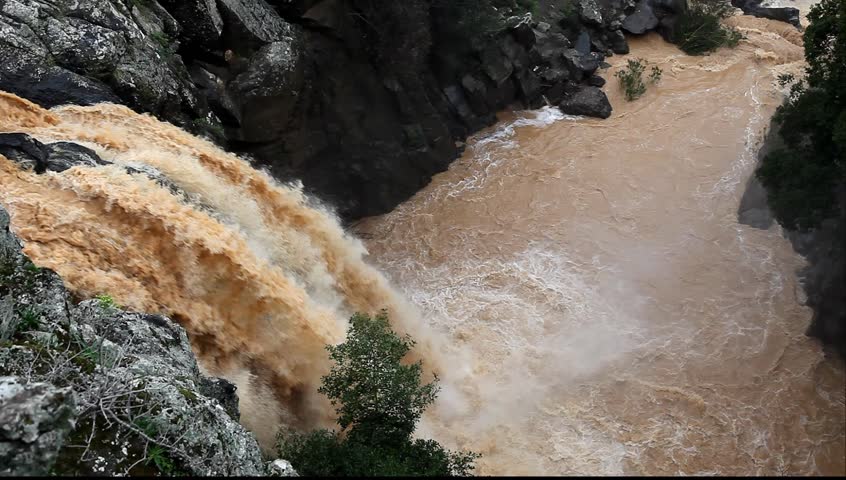 Banias Falls in the winter at the Golan Heights (Israel). Orange color of water because of washout of the earth from fields as a result of heavy rains. 