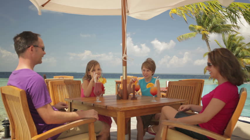 family cheering with drinks on tropical terrace 