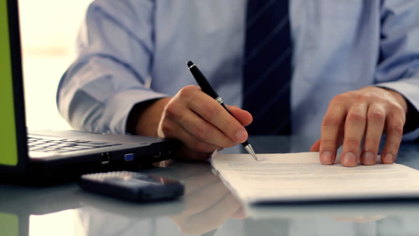 Businessman signing documents on reflective table