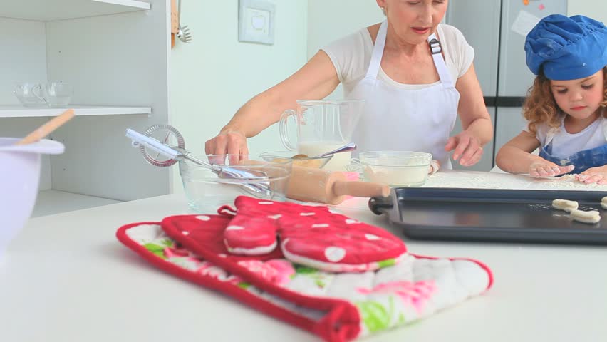 Grandmother and her grand daughter baking together in the kitchen