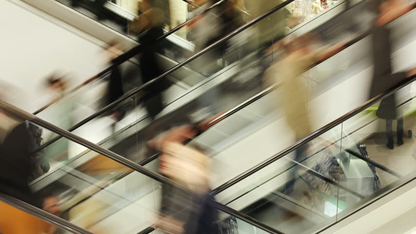 People on fast moving escalator in public building  