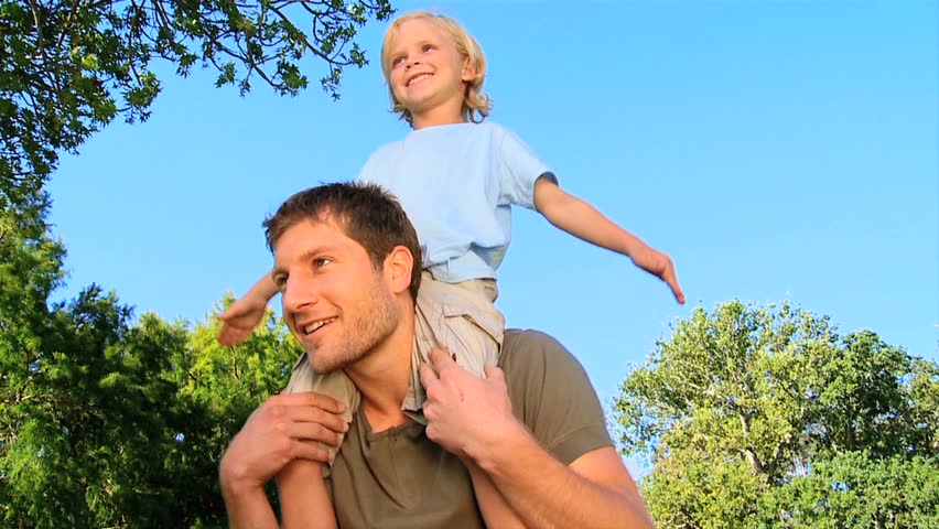 Handsome man giving a piggy back to his son outdoors