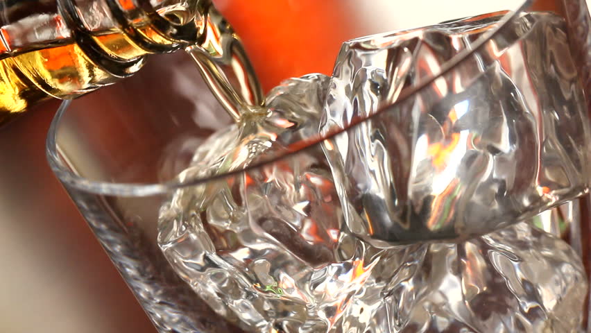 Pouring a scotch whiskey on the rocks close up