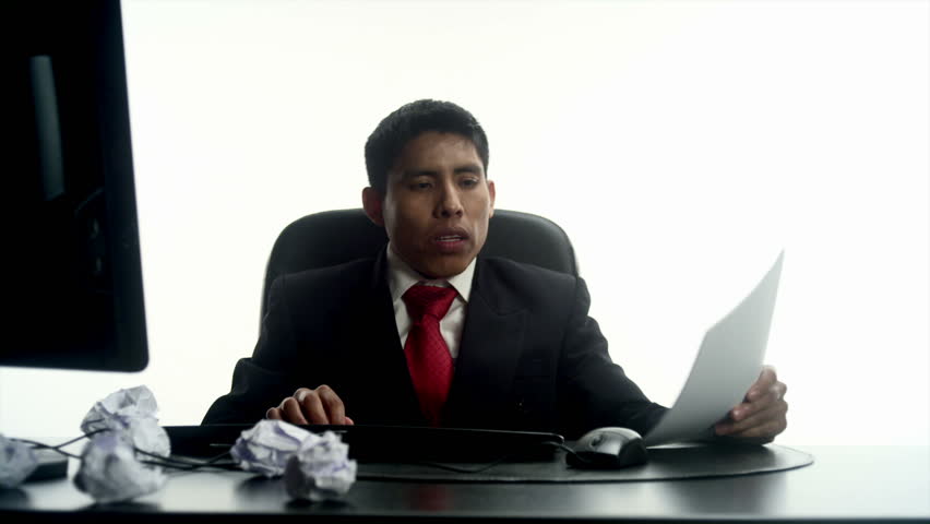 An Hispanic man crumples notes in his office 