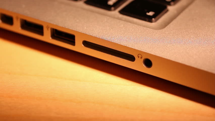 Extreme close up of someone inserting and removing an SD card into a laptop computer.