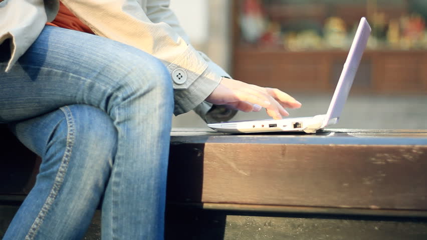 Woman with laptop sitting in urban environment, camera stabilizer shot 