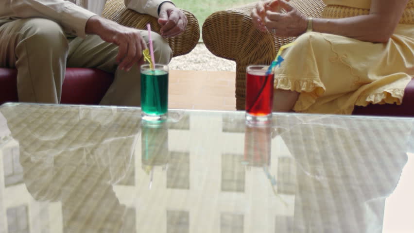 senior caucasian couple sitting in bar at hotel with cocktails and talking