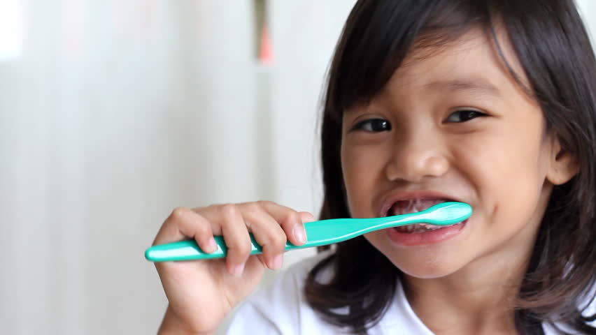 young kid brushing her teeth