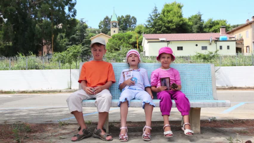 Three children, a boy and two girls sitting on the bench