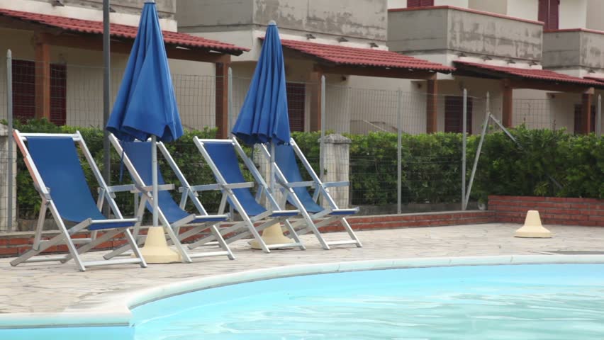 Several deckchairs facing the pool against the backdrop of an unfinished hotel 