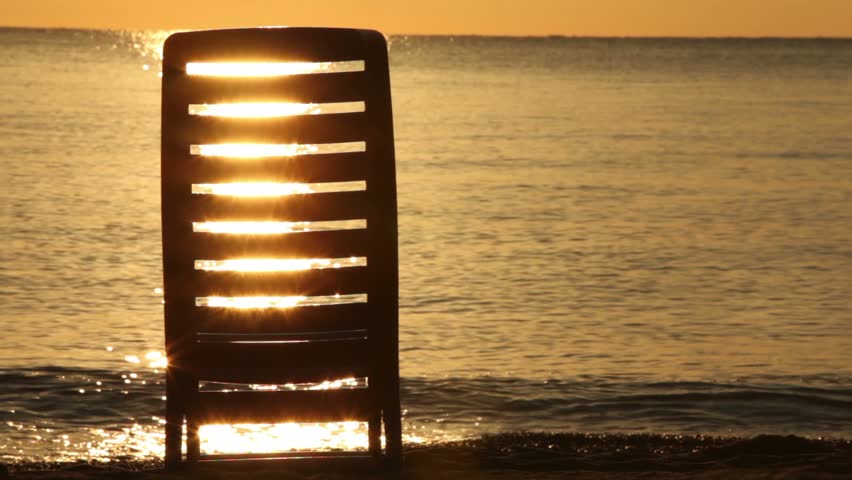 Deckchair stand in water and sunshine patterns shine through it