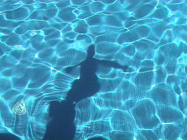 Shadow of young boy diving in the swimming pool