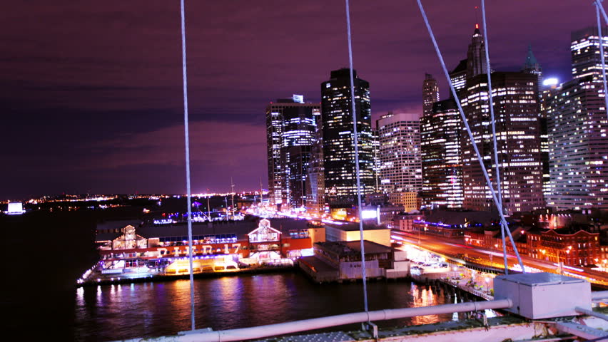 timelapse of brooklyn bridge with lower manhattan skyline in the the background at night
