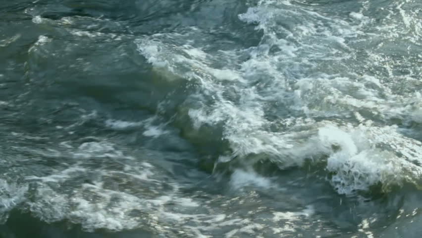 Crossing streams of wild river form small waves and combining with each other flowing on. 