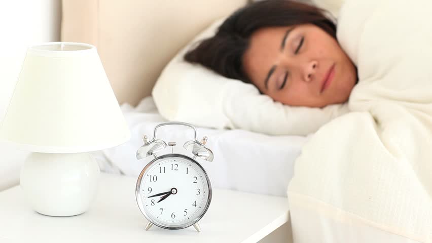 Cute woman waking up with an alarm clock