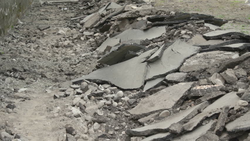 Down view of broken asphalt. On the right side there are larger parts, of the left hand it's more dust. 