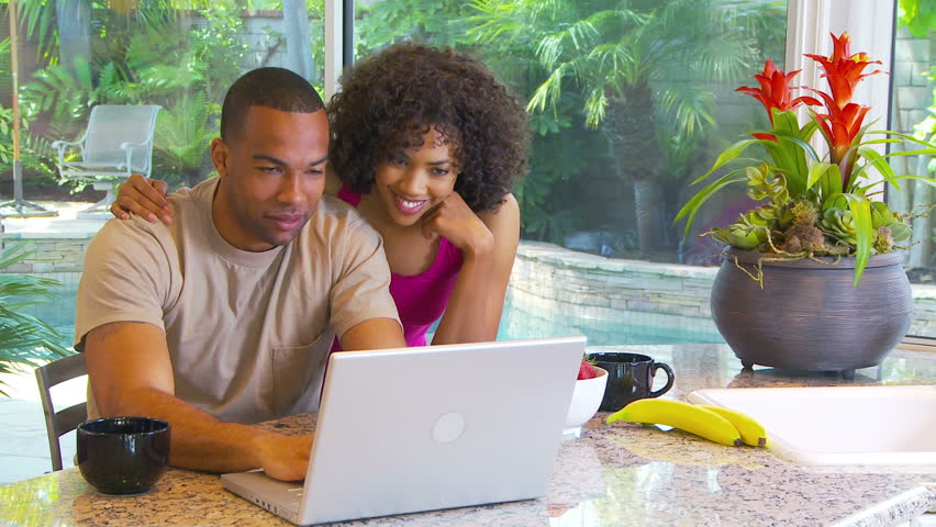 Couple using computer at kitchen counter