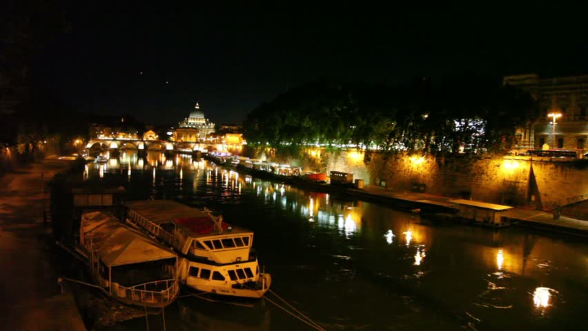 Sant Angelo Bridge  and Sant Peters Cathedral view from afar at night, Tiber river flow and two ships moored on quay are also shown