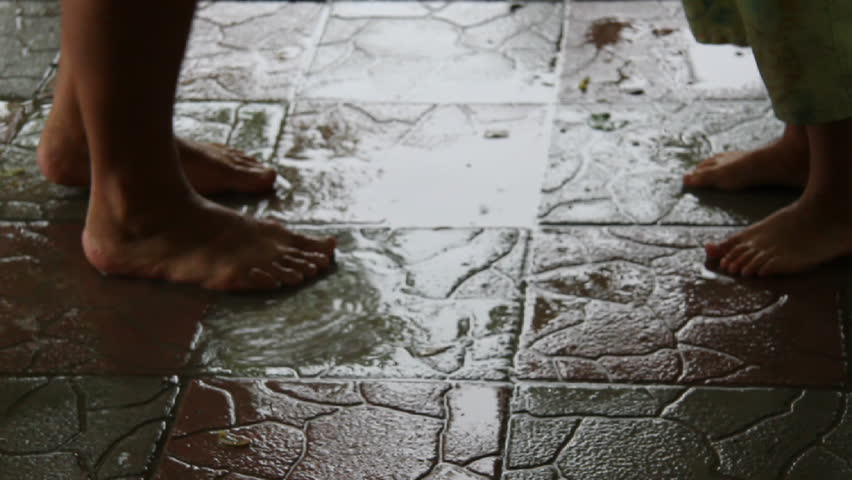children and mother having fun in puddle under rain