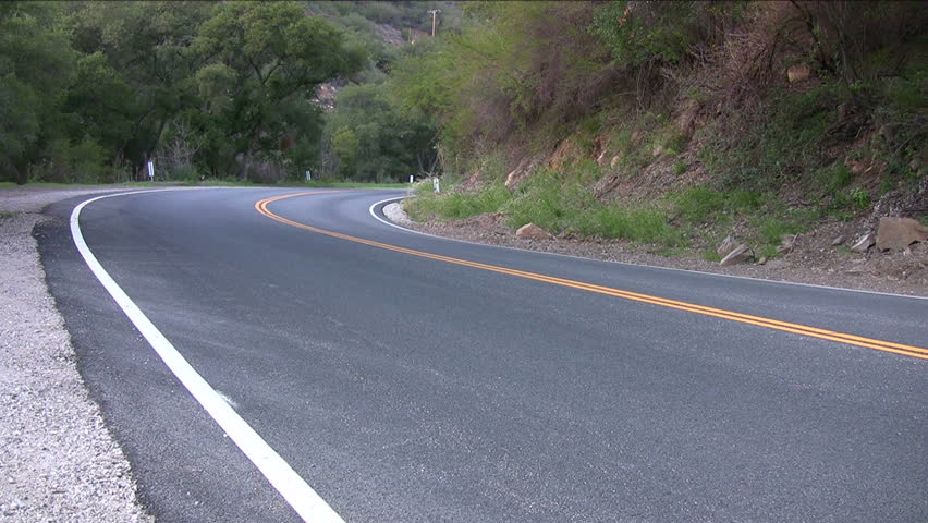 Motorcycle coming around the bend on a country road.