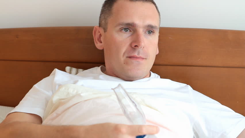 Sick man laying in his bed in home using inhaler also called nebulizer