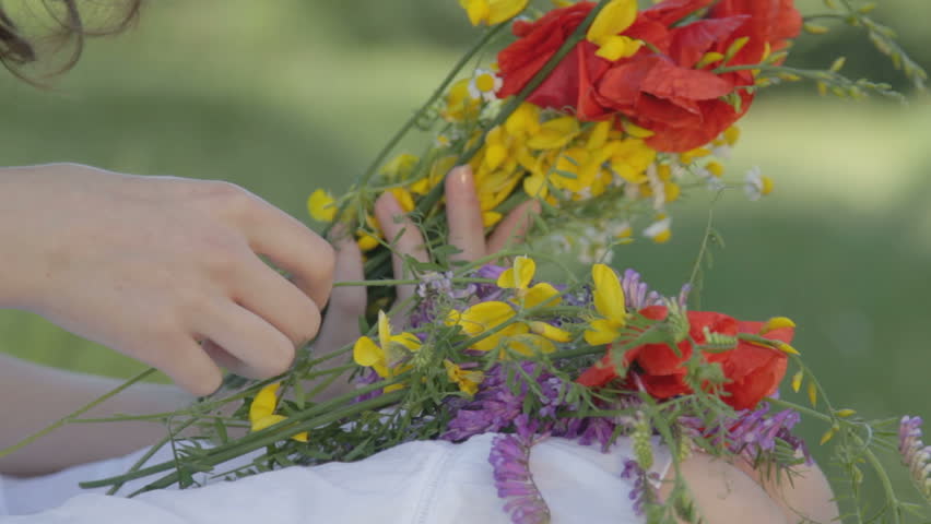 Young woman makes bouquet of flowers in forest