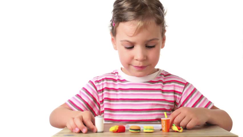 Girl puts on tray artificial food one by one, which are small copy of fast food