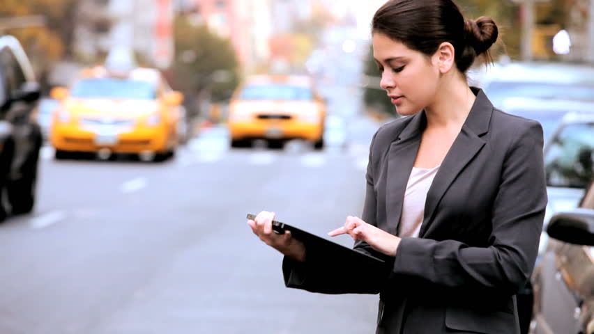 Young businesswoman in city clothes on the streets of New York working with a modern wireless tablet