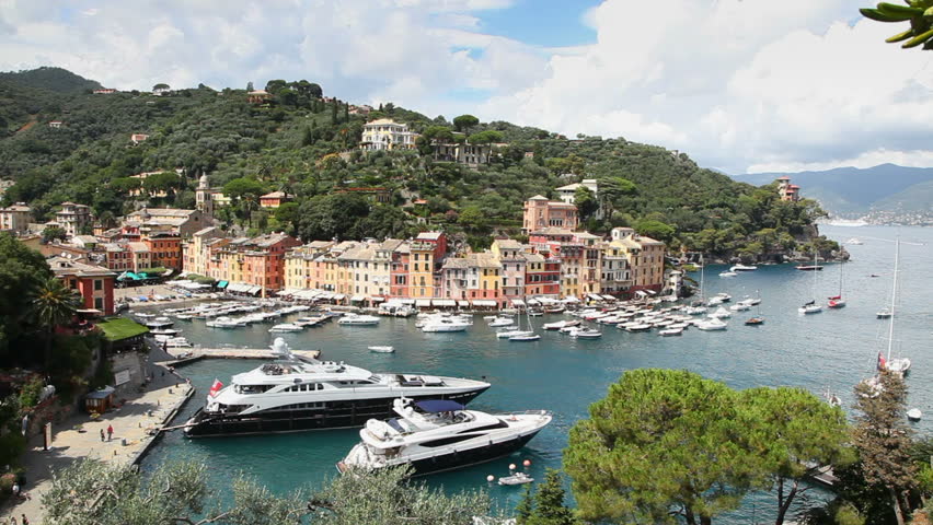 City view of the famous village of Portofino and its port with boats and sailboats, Italy. Two shots, sequence