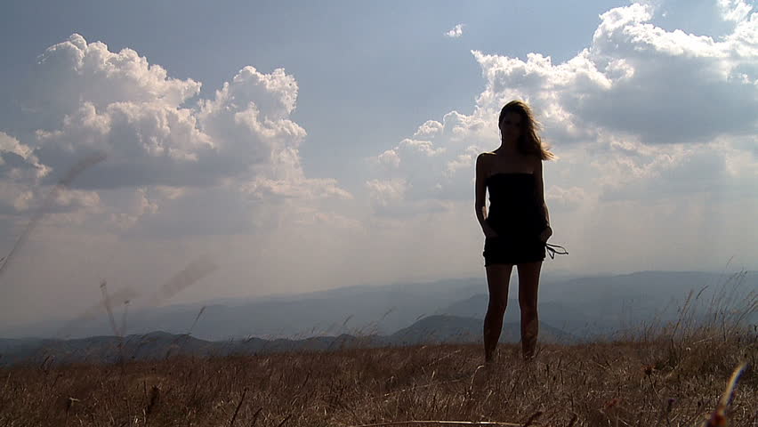 Young woman standing alone in field.