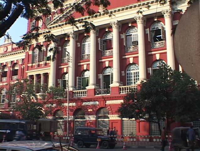 Pedestrians pass in front of a colonial style office building.