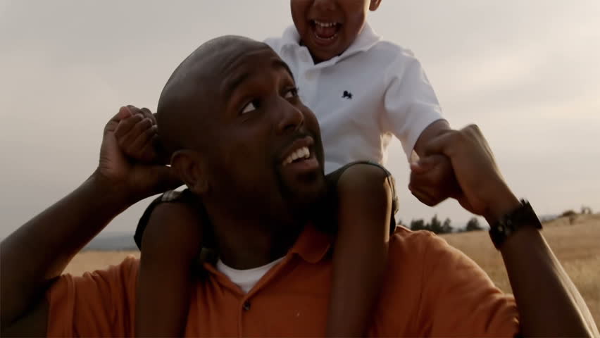 A father and son play in a wheat field on a sunny day.
