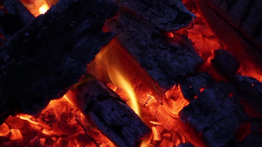 Burning wood that is charred black with white ash, glowing embers and dancing flames. Shot in 1920x1080 widescreen at night. Looping.