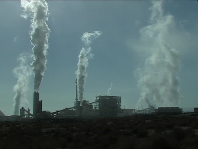 Smoke belches from smokestacks in an industrial area.
