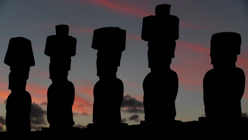 The sun sets behind Easter Island statues.