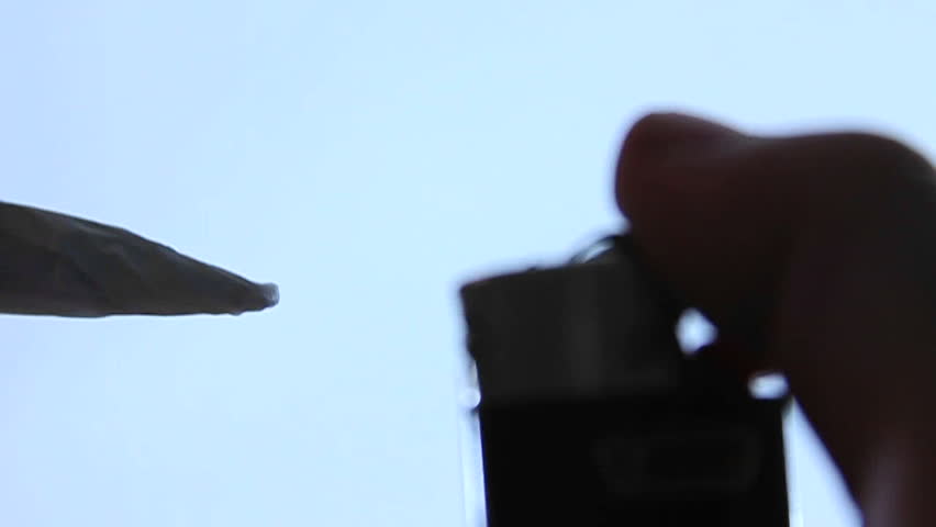 A person lights a joint and takes a draw.