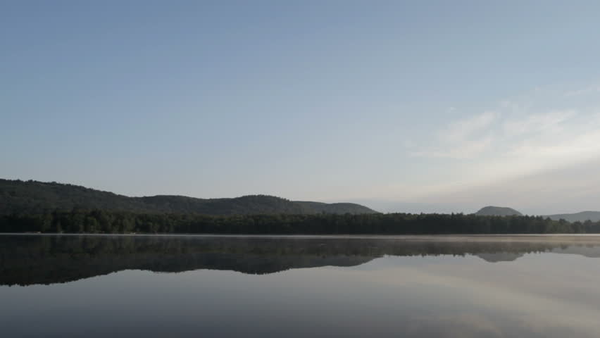 dead calm water shows gentle rippling reflection of Adirondack mountains,Lows Lake, Adirondack state park,New York,USA.