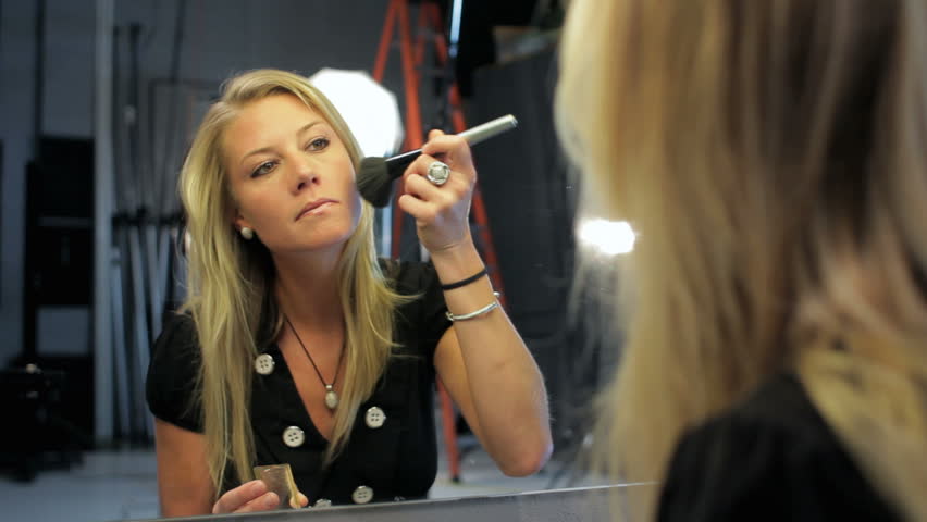 Pretty woman putting on makeup before a photo shoot