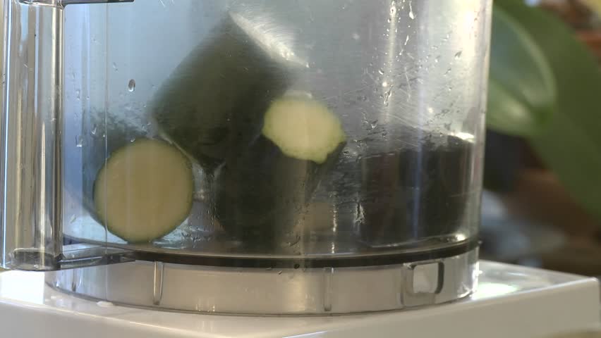 Close up of zucchini being chopped in a food processor.