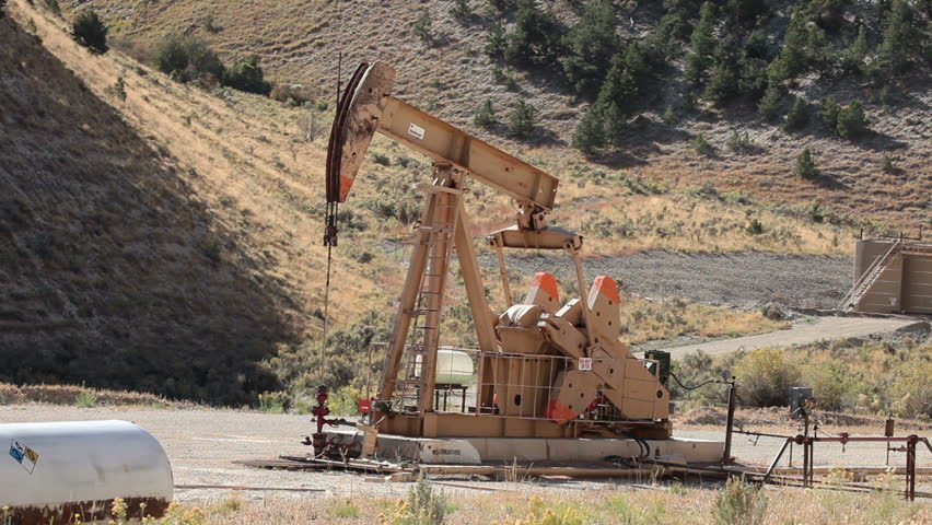 Oil well pumping crude from deep valley between mountains in central Utah. Propane motor powers the pump that extracts the oil.