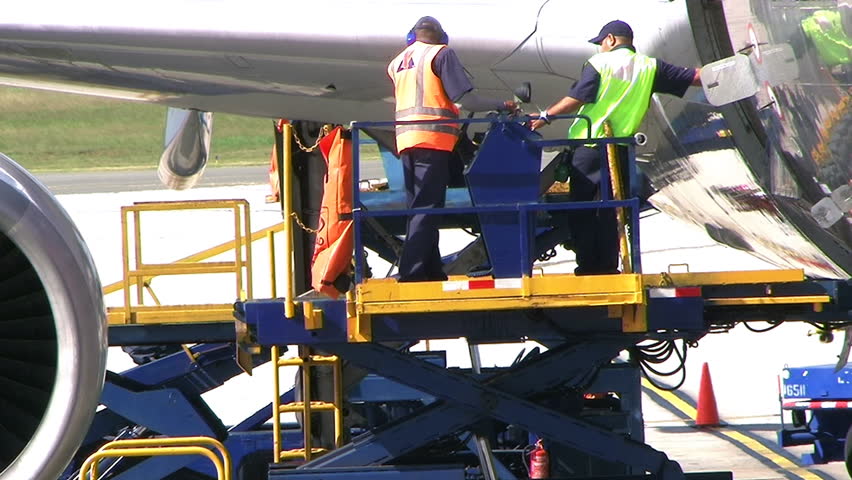 DOMINICAN REPUBLIC - CIRCA APRIL 2009: Ground crew accessing airplane cargo area at Las Americas International Airport.