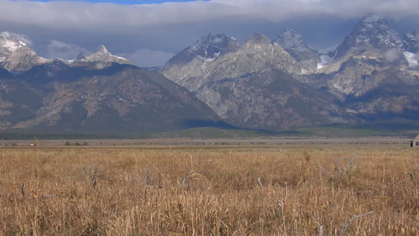 An old barn rises out of a prairie with the Grand Tetons in the background