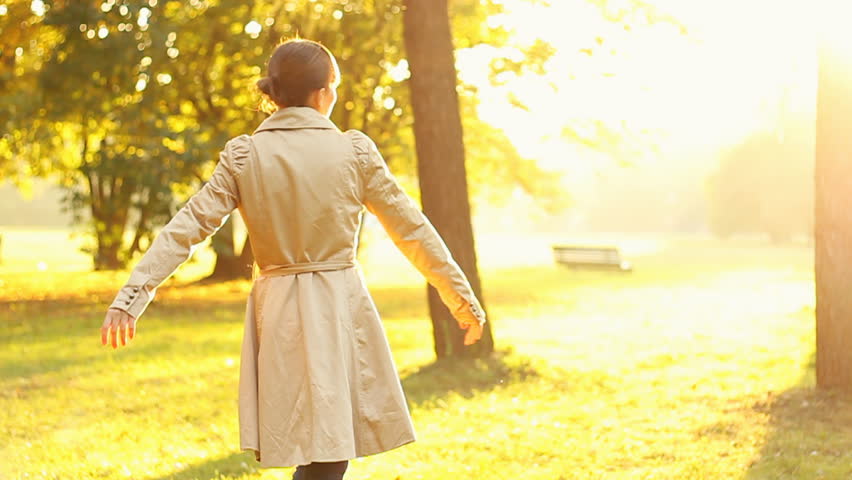 Young happy woman spinning  in beautiful autumn park, slow motion