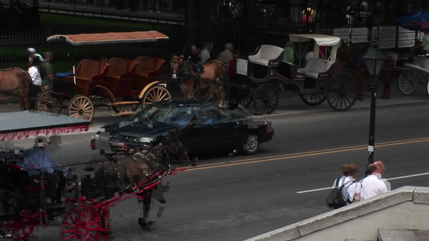 NEW ORLEANS - CIRCA 2009: Mule-drawn buggies wait for tourists, while another buggy makes its way down a crowded street in New Orleans.